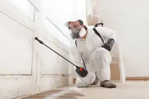 Pest control technician from Prestige Pest Unit inspecting and treating a residential property in Sussex County, New Jersey, wearing protective gear and handling professional pest control equipment.
